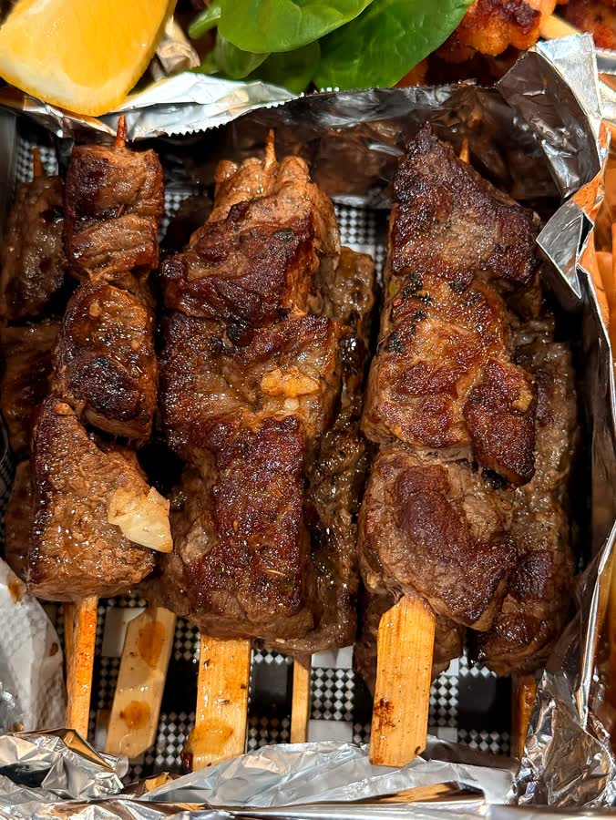Grilled meat skewers in a foil-lined box
